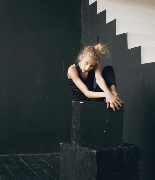 Woman performing a light cardio exercise in a calm, dark studio with cyan light.